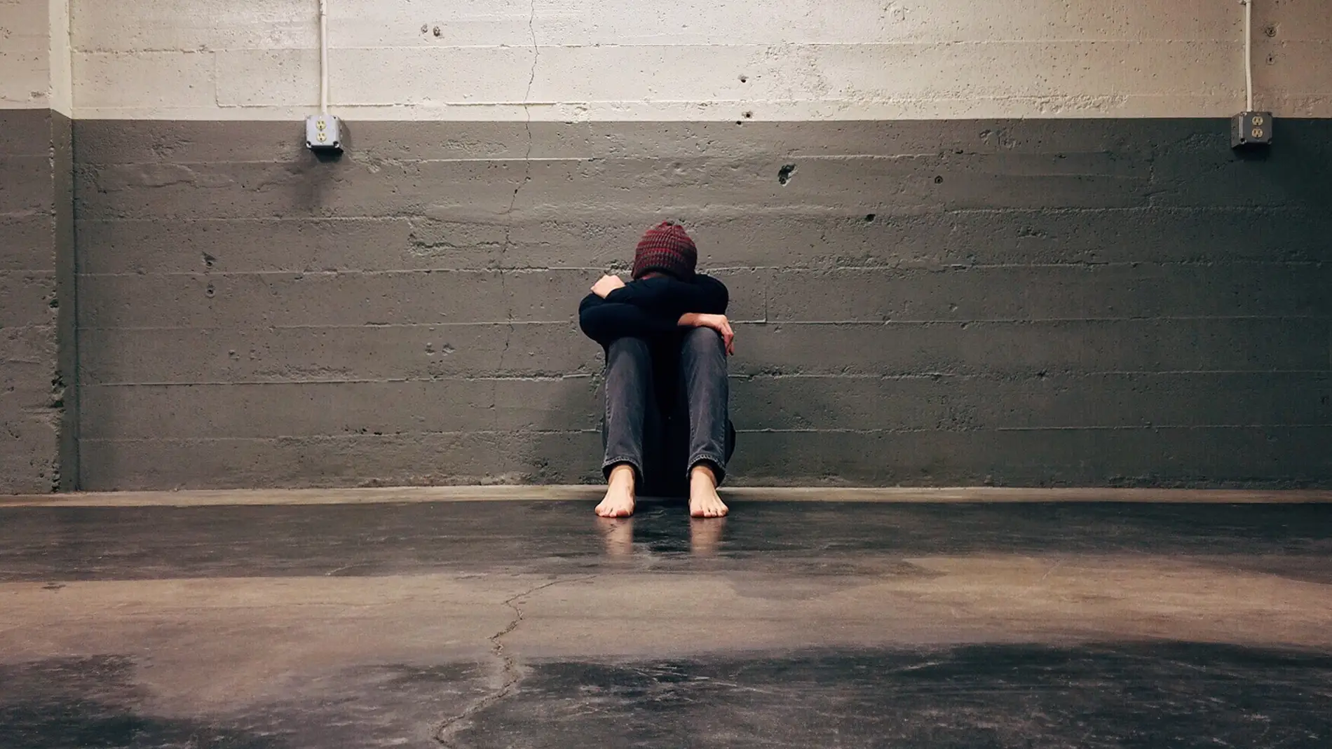 Persona con depresión sentada en un garaje