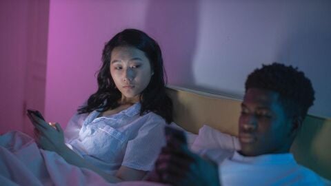 Una pareja mirando el móvil en la cama