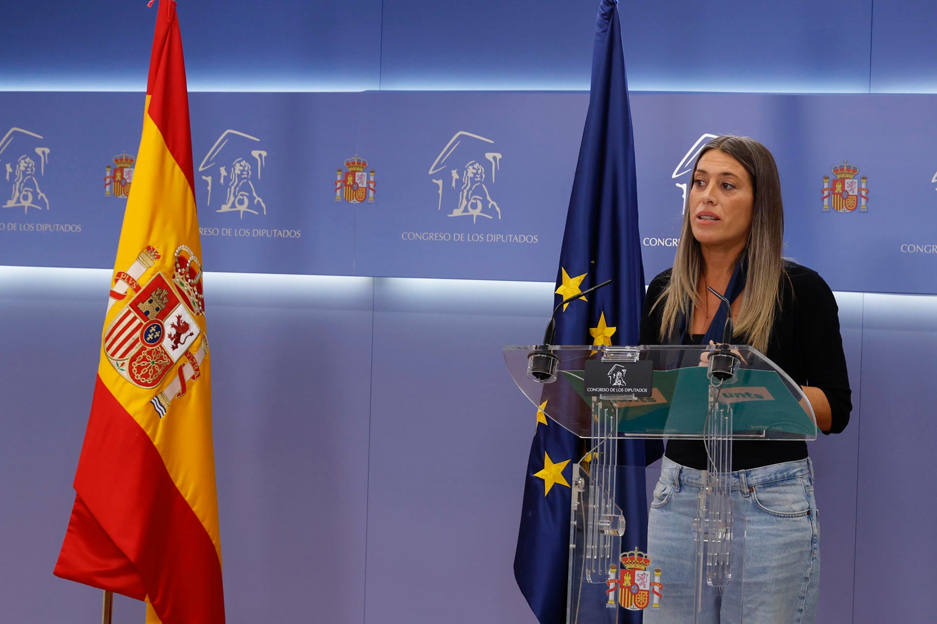 Míriam Nogueras desplaza la bandera de España antes de comparecer en la sala de prensa del Congreso Míriam Nogueras desplaza la bandera de España antes de comparecer en la sala de prensa del Congreso