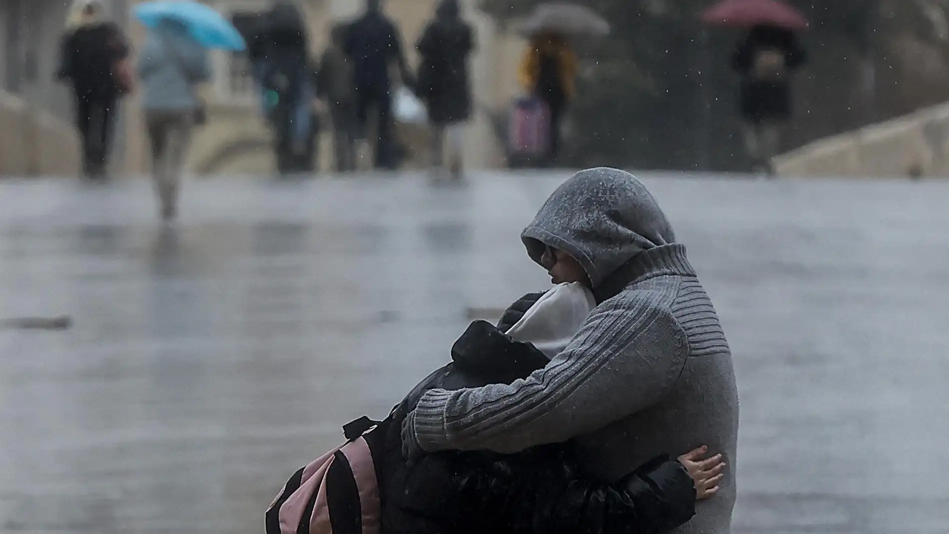 Una pareja se abraza mientras llueve.