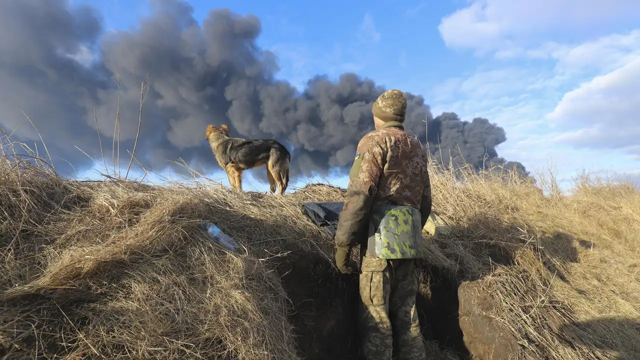 Un militar ucraniano observa junto a su perro una columna de humo negro cerca de Kiev Un militar ucraniano observa junto a su perro una columna de humo negro cerca de Kiev