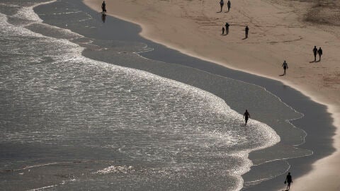 Varias personas pasean por la playa de La Concha en Suances.