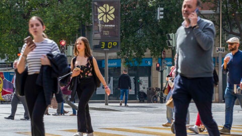 Varias personas cruzan un paso de peatones junto a un term&oacute;metro que marca 30 grados, este viernes en la Gran V&iacute;a de Murcia