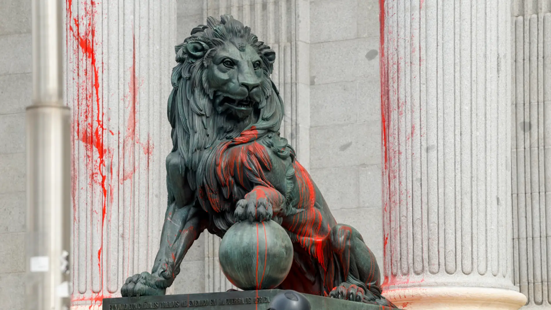 Un grupo de activistas lanza pintura roja contra los leones del Congreso de los Diputados