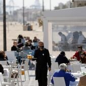 Un camarero atiende las mesas de una terraza en uno de los restaurantes de la playa de la playa de la Malvarrosa de Valencia