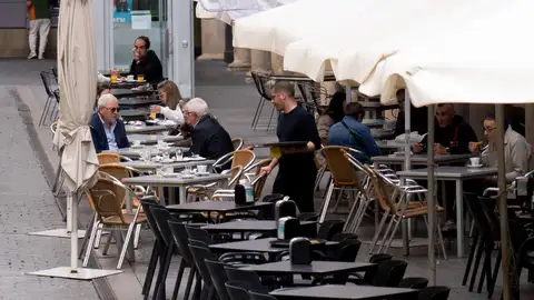 Un camarero atendiendo las mesas en una terraza Un camarero atendiendo las mesas en una terraza