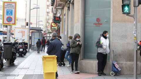 Un fila de personas espera a entrar en el economato solidario de C&aacute;ritas situado en la calle Bravo Murillo de Madrid.