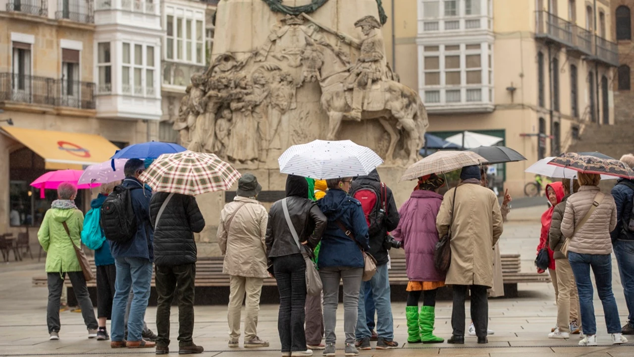 Un grupo de turistas se protege de la lluvia con sus paraguas en el centro de Vitoria
