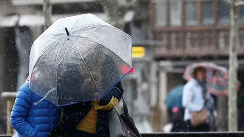 Dos personas se protegen con un paraguas ante la lluvia. Dos personas se protegen con un paraguas ante la lluvia.