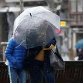 Dos personas se protegen con un paraguas ante la lluvia. Dos personas se protegen con un paraguas ante la lluvia.