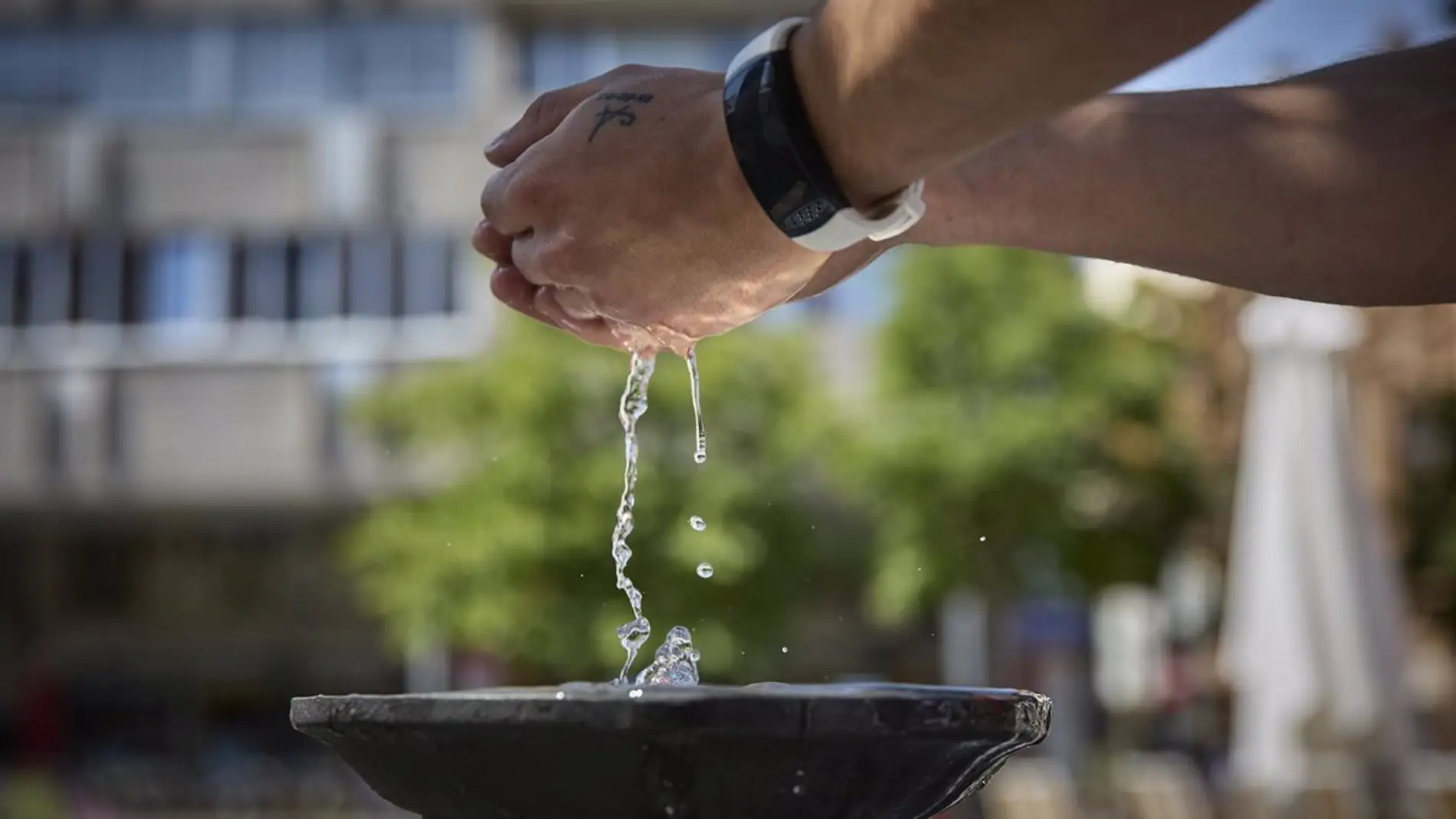 Una persona coge agua de una fuente
