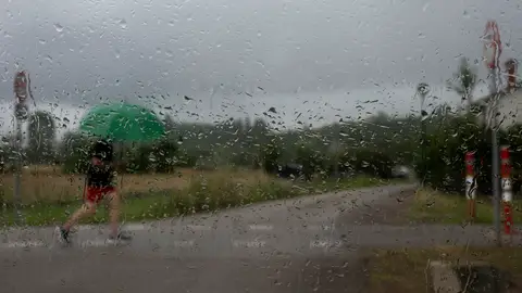 Un hombre camina bajo la lluvia en Cantabria Bajada de temperaturas, inestabilidad y tormentas: así será el tiempo en julio