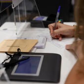 Una mujer cumplimenta la documentación para ejercer el voto por correo en una oficina de Madrid