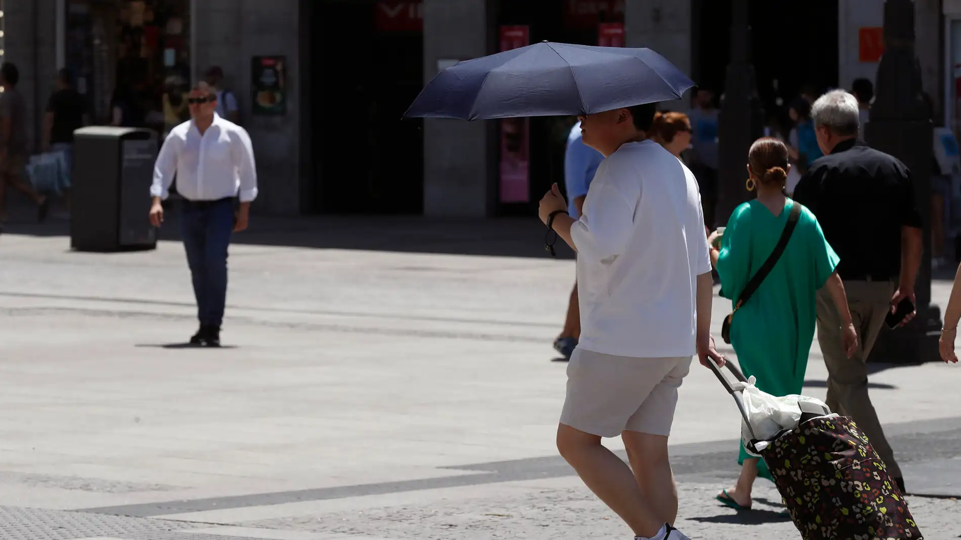 Un hombre se protege del sol con un paraguas en Madrid.