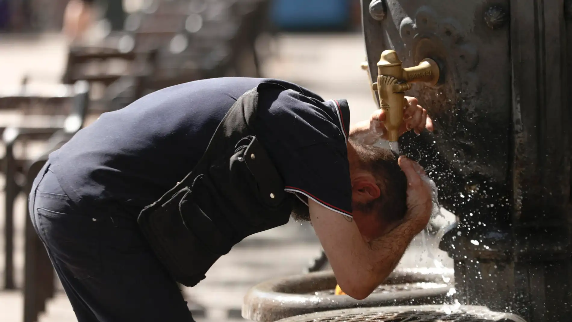 Un hombre se refresca en una fuente en el centro de Barcelona.