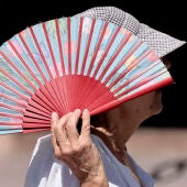 Una mujer se protege con un abanico del sol en Valencia.