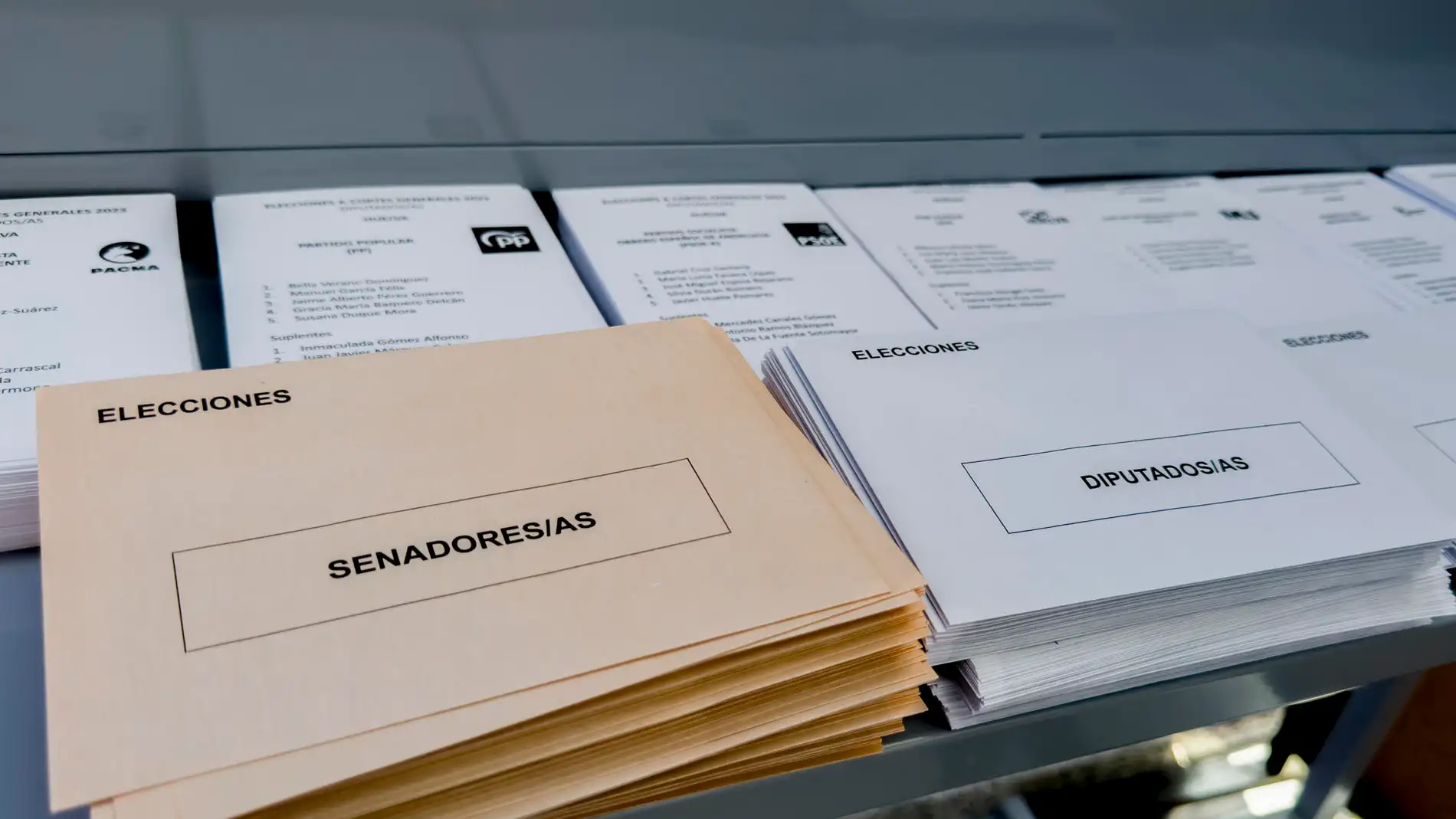 Papeletas, sobres, mesas y agua, dispuestos en un colegio electoral