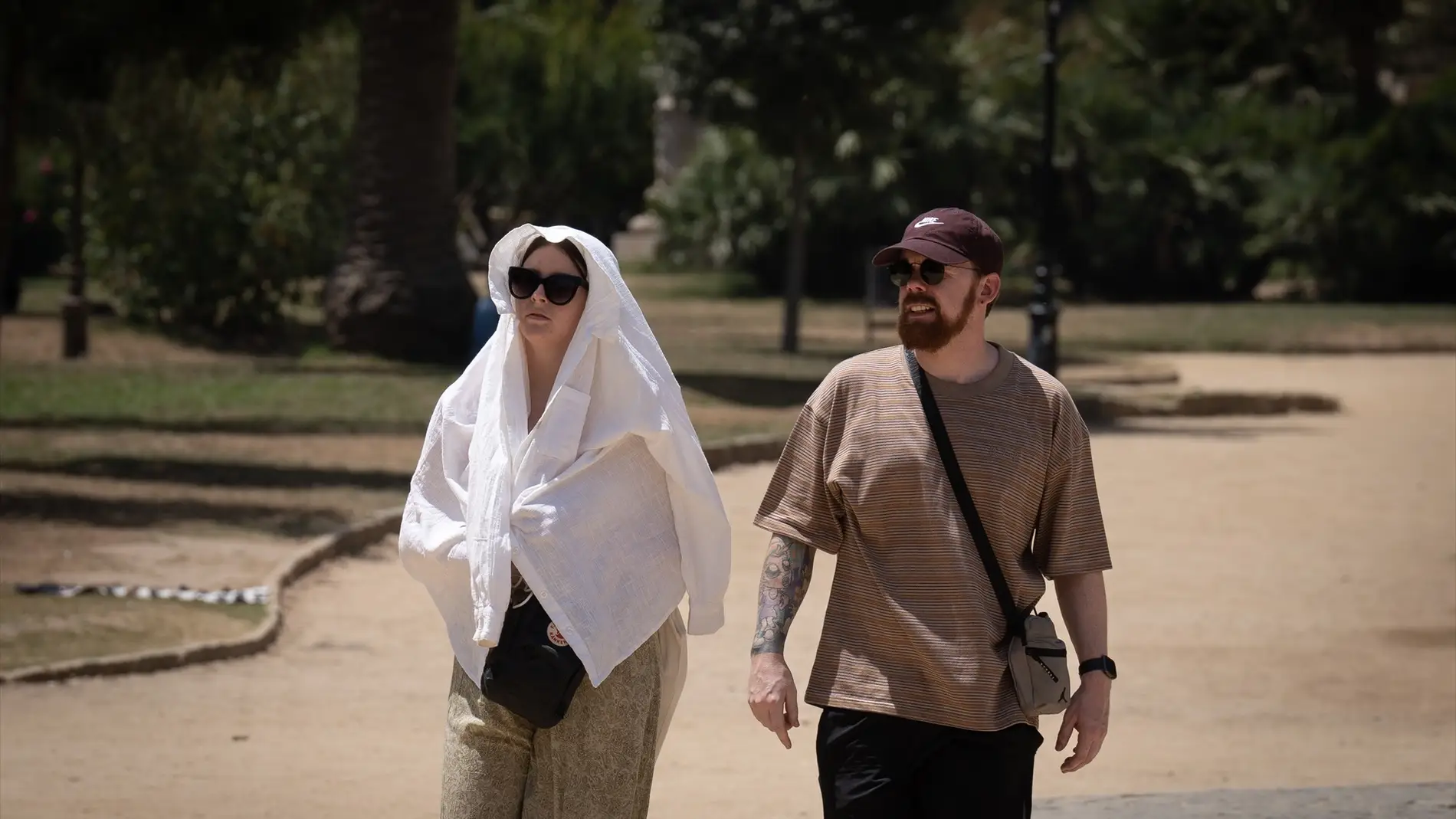 Dos viandantes se protegen del calor en el Parque de la Ciudadela (Barcelona) 