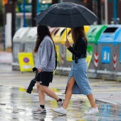 Dos chicas caminan por la calle bajo un paraguas