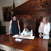 Carmen Susín firma el libro de visitas del Ayuntamiento ante la mirada de Lorena Orduna y Susana Oliván.
