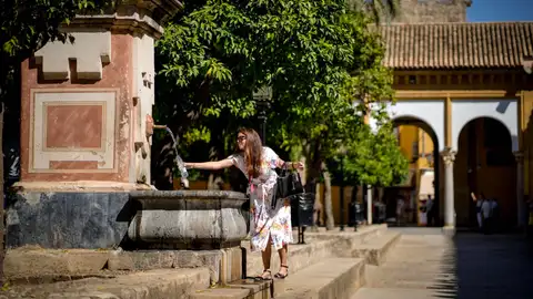 Una mujer rellena una botella de agua en el patio de Los Naranjos de la Mezquita-Catedral de Córdoba Una mujer rellena una botella de agua en el patio de Los Naranjos de la Mezquita-Catedral de Córdoba