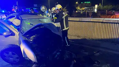 Cuatro jóvenes resultan heridos tras el choque de su vehículo con el muro de la rotonda de Felipe IV en Alcalá de Henares Bomberos de la Comunidad de Madrid trabajan para liberar al conductor de un vehículo tras un accidente