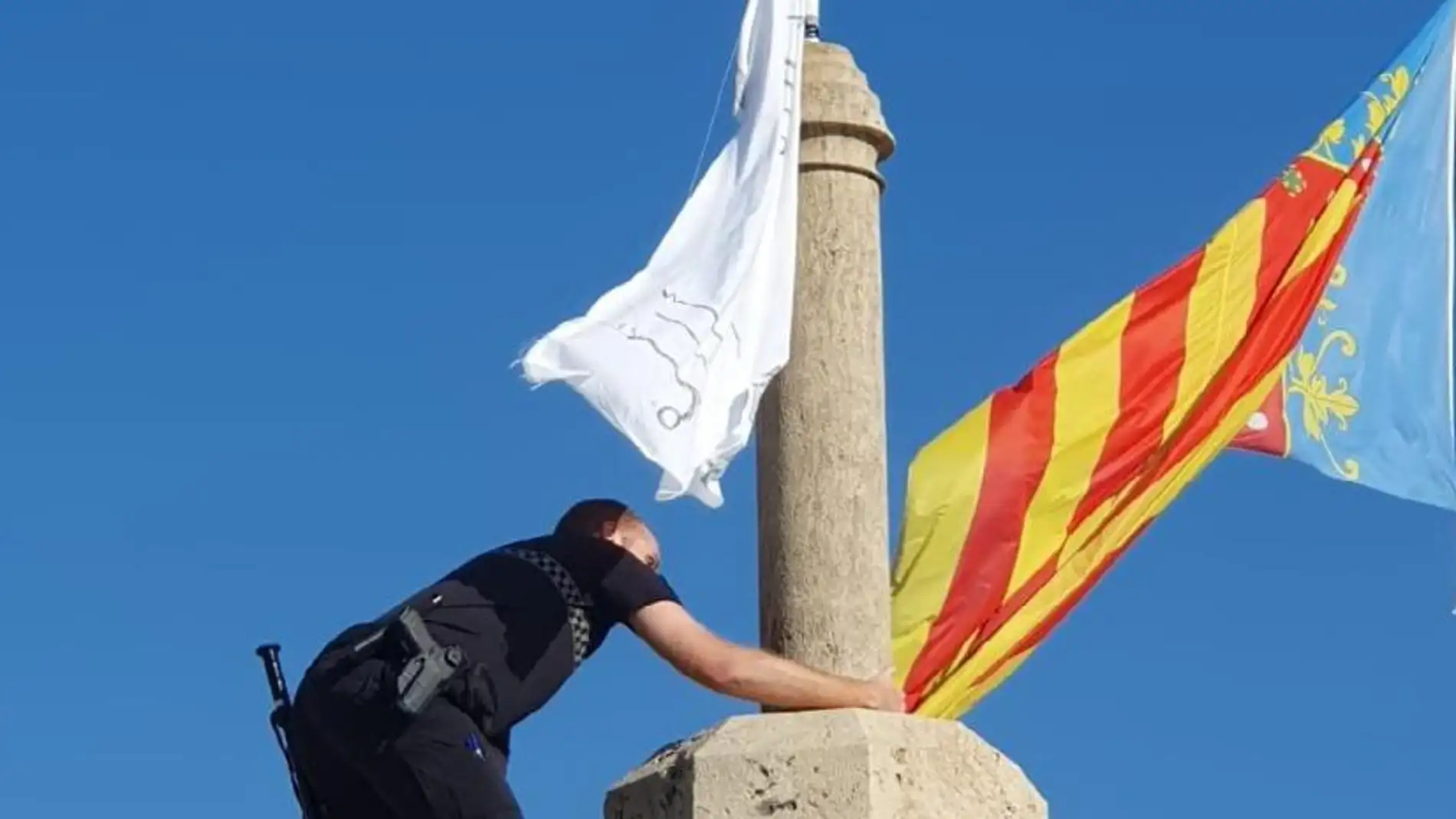 Un agente de la Policía Local de València retira una bandera con versos del Corán.