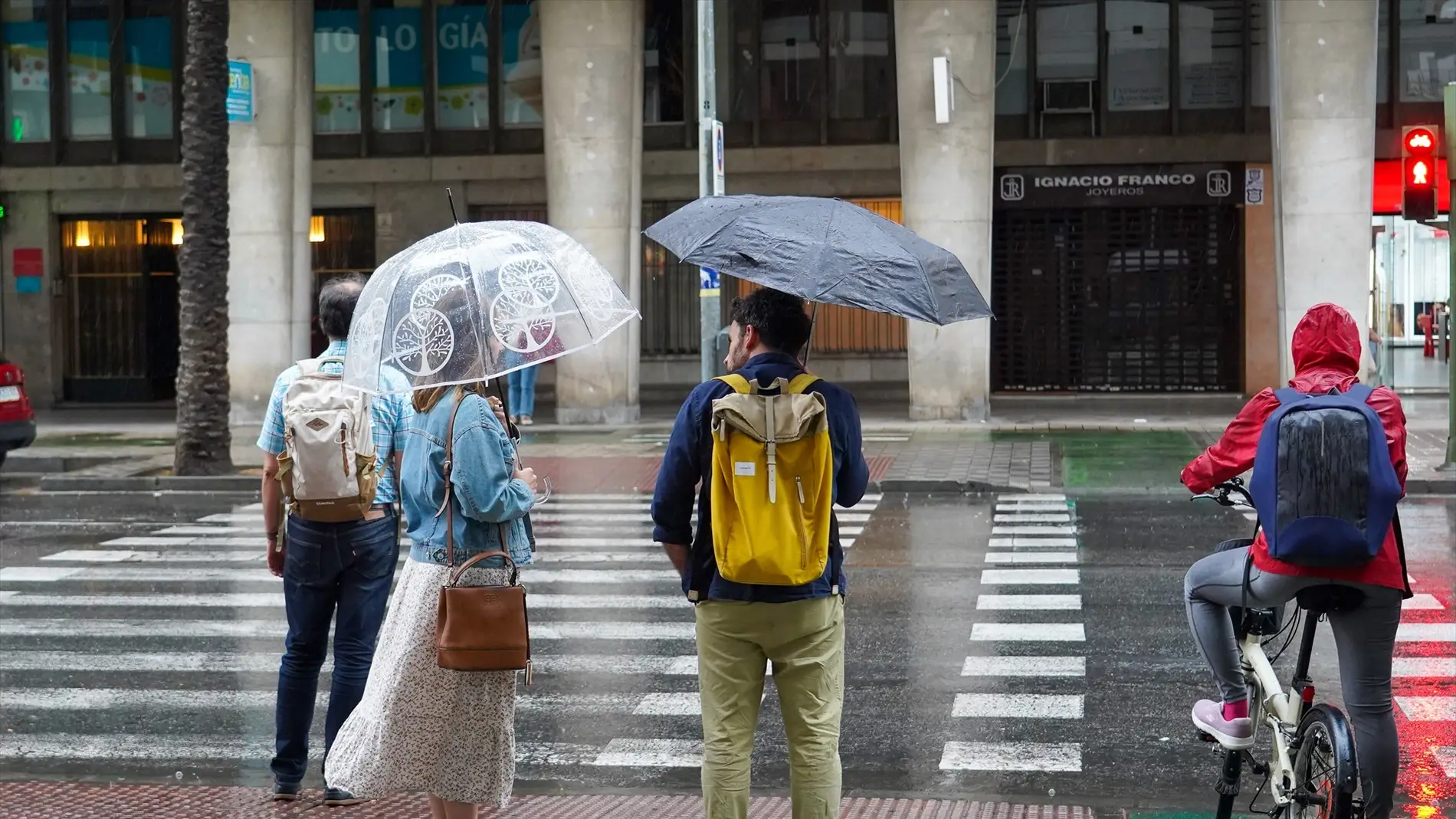 Viandantes por las calles de Sevilla con paraguas abiertos.