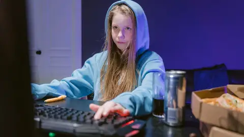 Una adolescente delante del ordenador consumiendo una bebida energética o estimulante Una adolescente delante del ordenador consumiendo una bebida energética o estimulante