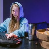 Una adolescente delante del ordenador consumiendo una bebida energética o estimulante