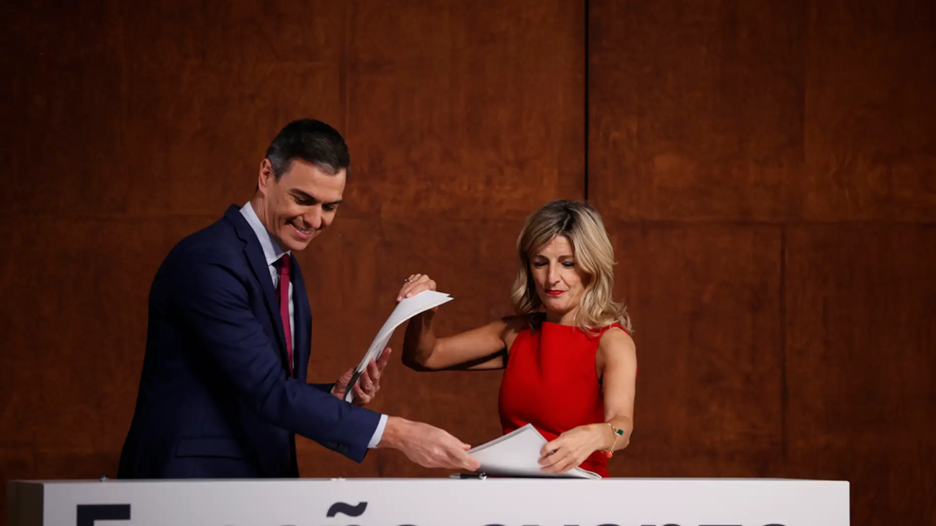 Pedro Sánchez y Yolanda Díaz intercambiándose los documentos del acuerdo firmado por ambos/ EFE/ Emilio Naranjo