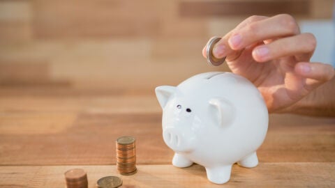 Imagen de archivo de una persona ahorrando dinero en la hucha