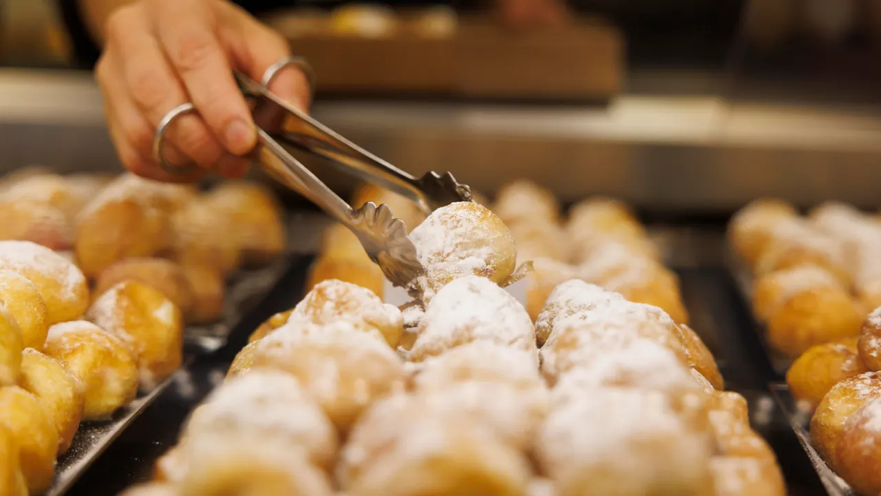 Una empleada coloca en una bandeja los tradicionales buñuelos de viento
