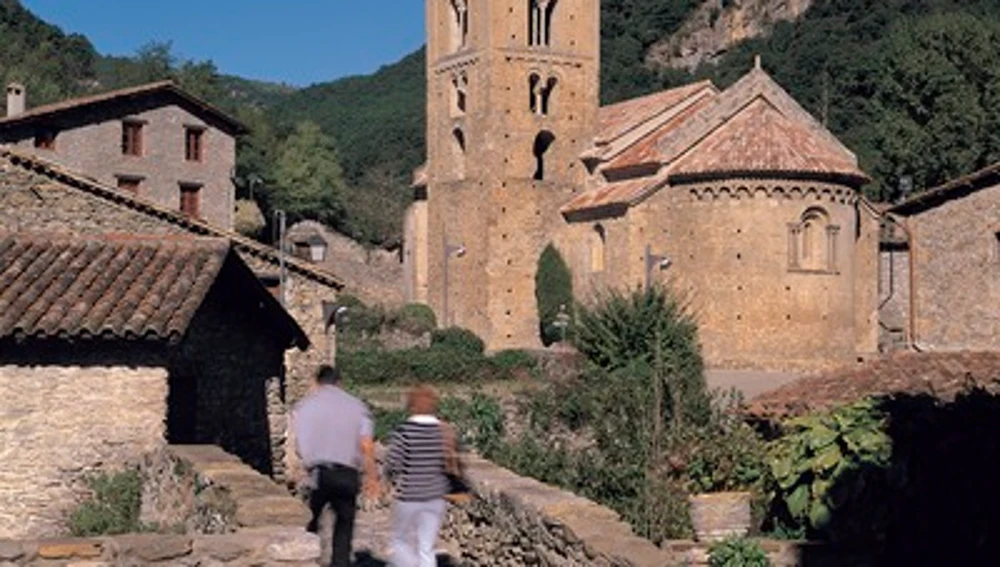 Dos personas caminan hacia la iglesia de Sant Cristòfor de Beget. 