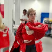 Integrante de Cruz Roja Alicante con la bebé que iba en la patera interceptada en Los Arenales del Sol de Elche.