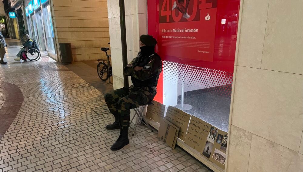 Un ilicitano vestido de militar hace guardia frente a la oficina del Banco Santander del centro de Elche