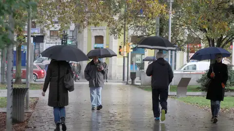 Imagen de archivo de varias personas paseando por la calle durante un día lluvioso y frío Imagen de archivo de varias personas paseando por la calle durante un día lluvioso y frío