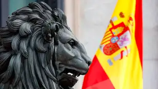 Una bandera de España es vista junto a uno de los leones del Congreso de los Diputados
