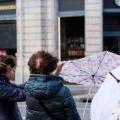 Varias viandantes se enfrentan a rachas de viento en una calle de Oviedo