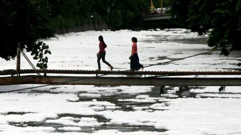 Imagen de archivo de dos ni&ntilde;as que atraviesan un puente que se levanta sobre un r&iacute;o contaminado en Yakarta./ EFE/Jurnasyanto Sukarno