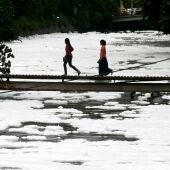 Imagen de archivo de dos niñas que atraviesan un puente que se levanta sobre un río contaminado en Yakarta.