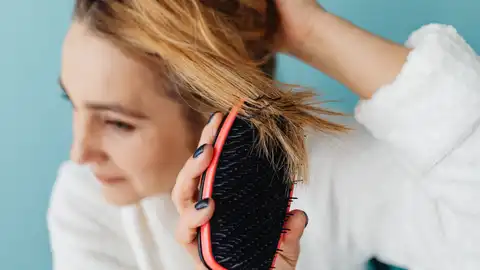 Una mujer peinándose Por qué se me cae tanto el pelo
