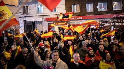 Decenas de personas con bufandas y banderas de Espa&ntilde;a celebran la entrada del a&ntilde;o nuevo, en la calle Ferraz