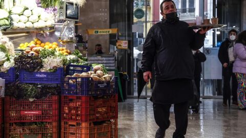 Archivo - Un camarero pasa por un puesto de fruta y verdura en el Mercado Central de Val&egrave;ncia - 