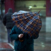 Imagen de archivo de un hombre tratando de protegerse contra la lluvia y el viento en València. 