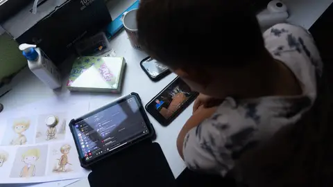 Un niño utilizando dos teléfonos móviles Un niño utilizando dos teléfonos móviles