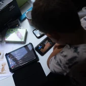 Un niño utilizando dos teléfonos móviles Un niño utilizando dos teléfonos móviles