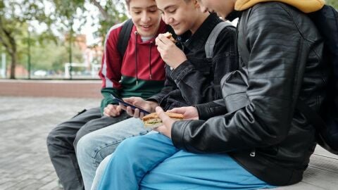 Adolescentes con un tel&eacute;fono m&oacute;vil