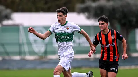 Héctor Peña, jugador del Elche Ilicitano, conduce el balón con la presión cercana de un defensor Agenda polideportiva del fin de semana en Elche y las comarcas del Vinalopó