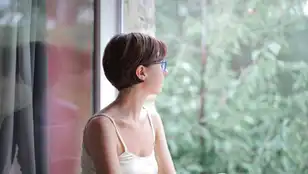 Una mujer mira por la ventana en una imagen de archivo